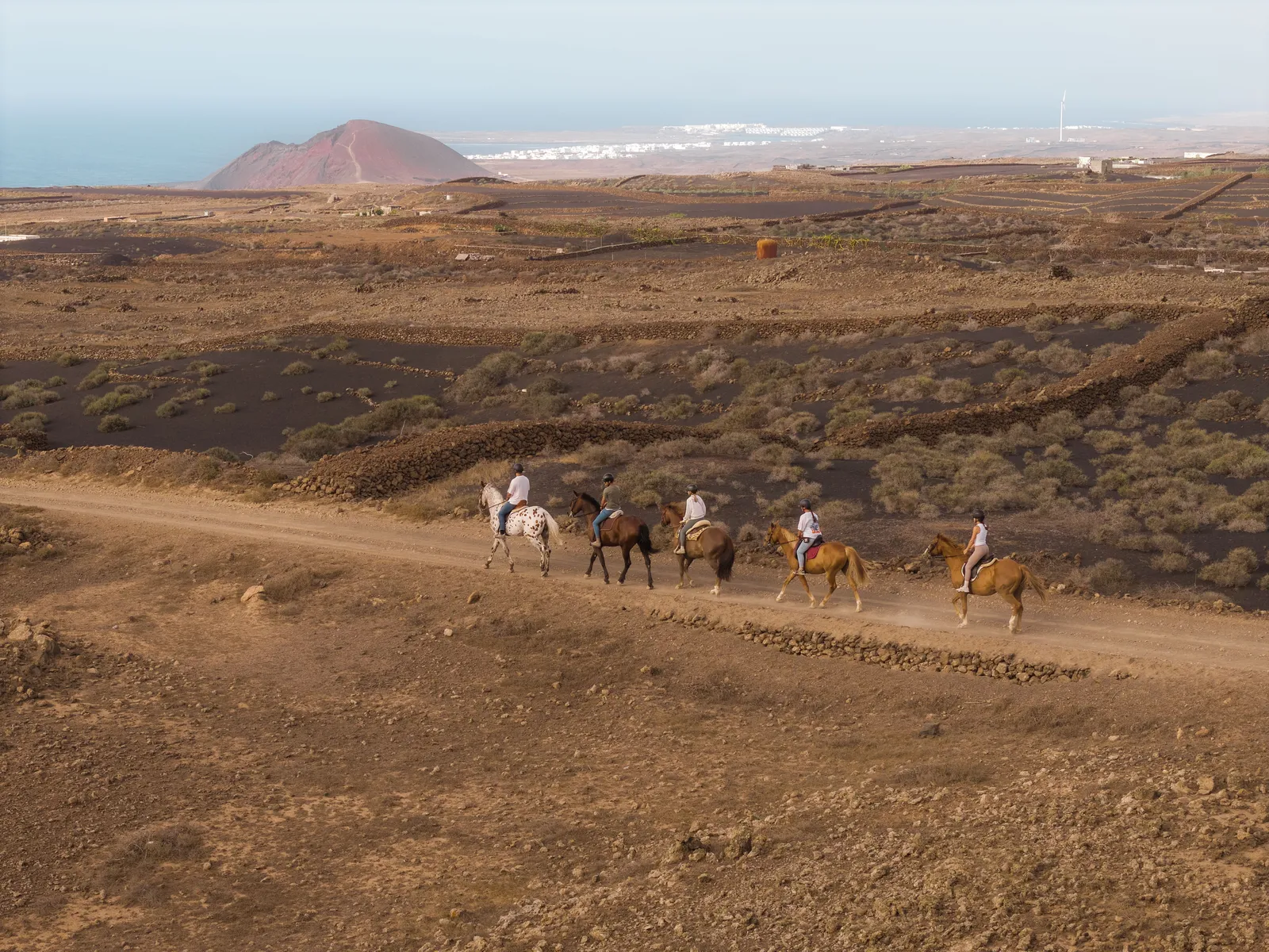 Riders on a ridge with the volcano and sea behind