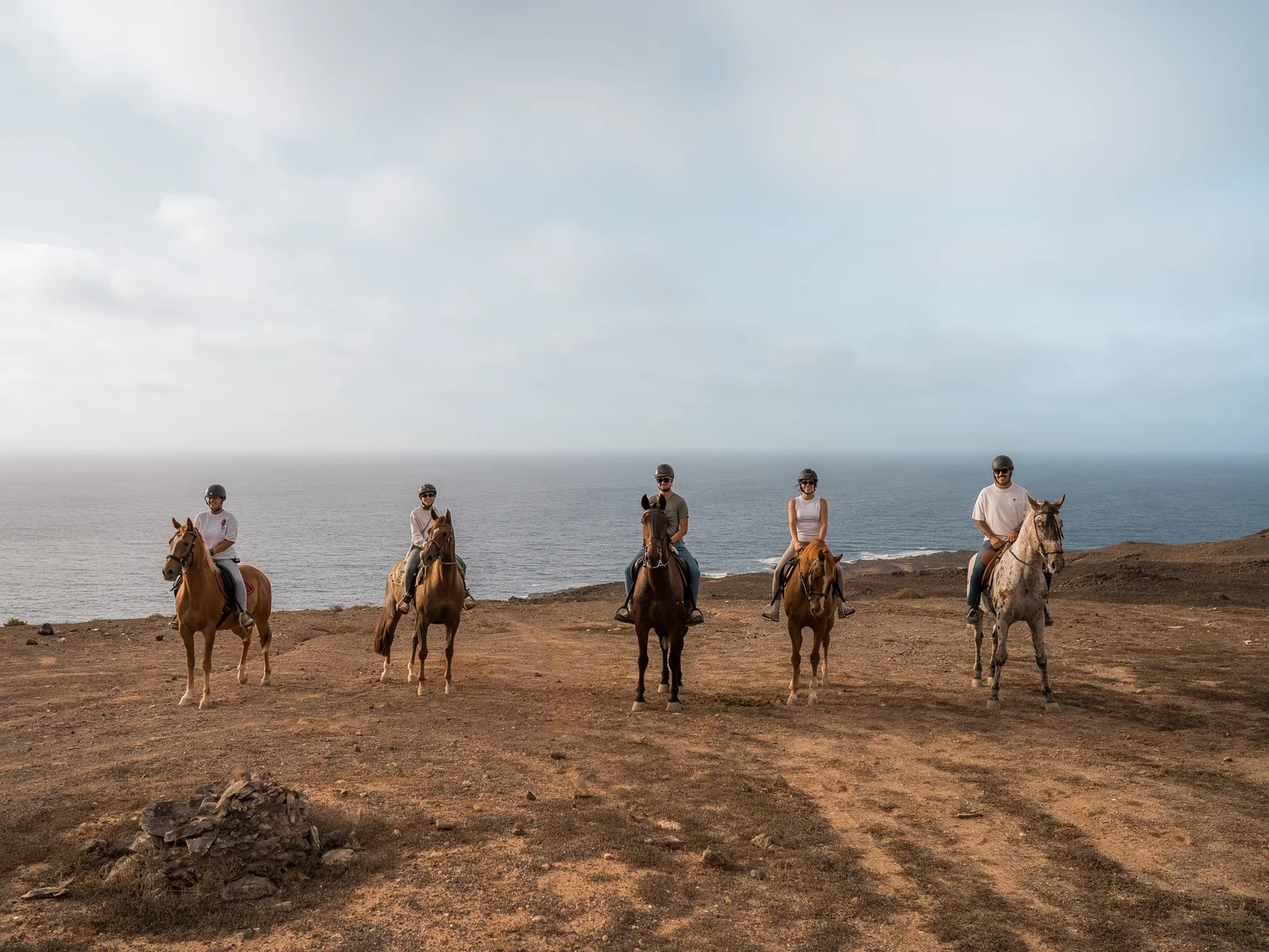A small group of riders walking their horses into the shallow sea on a Lanzarote beach